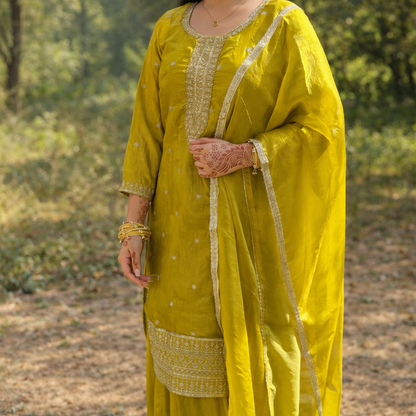 Woman in a yellow traditional outfit standing in a natural setting