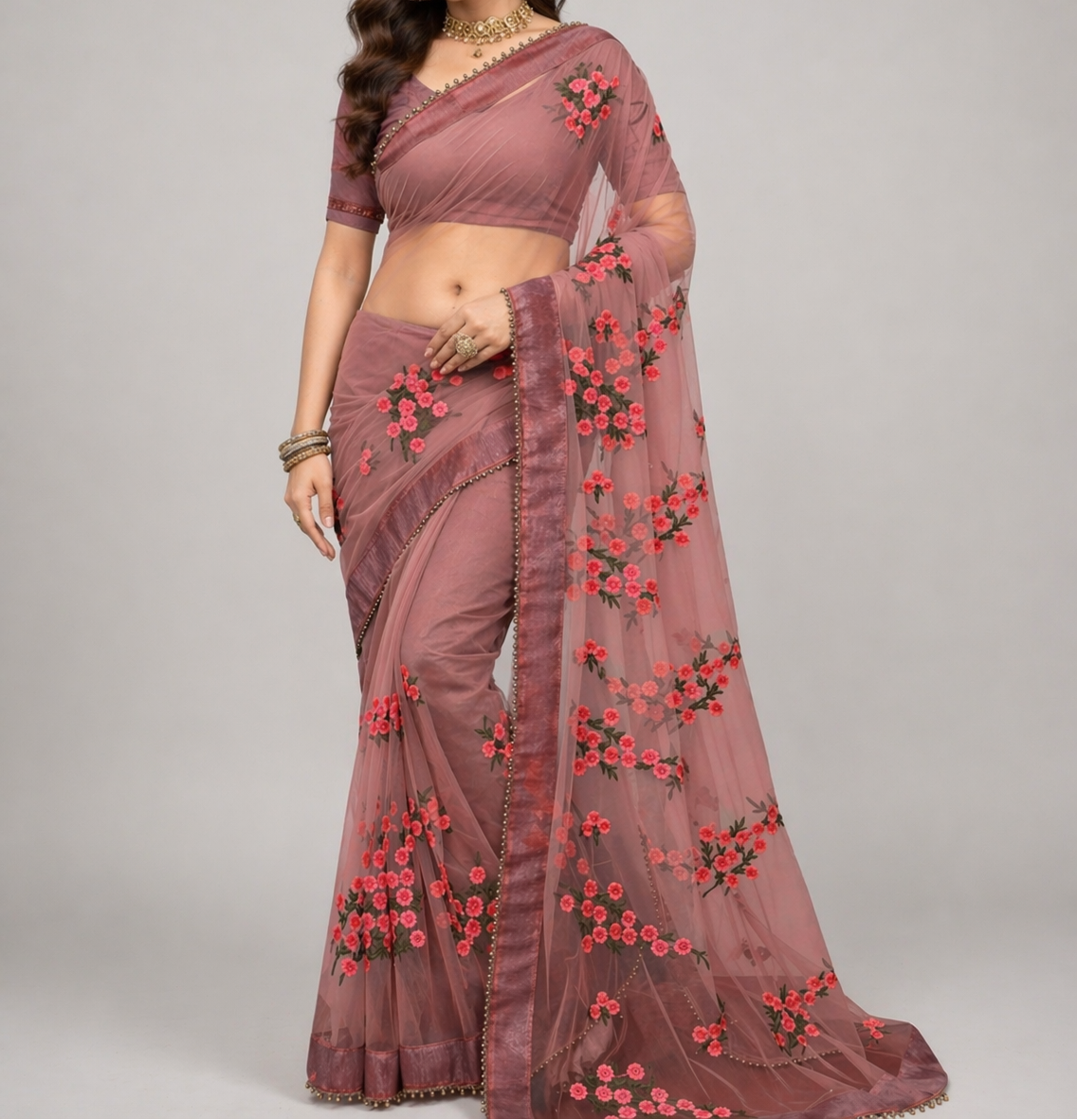Woman wearing a mauve saree with floral embroidery on a gray background