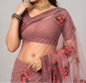 Woman wearing a mauve saree with floral embroidery on a plain background