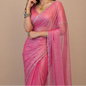 Woman wearing a pink saree with silver details against a beige background