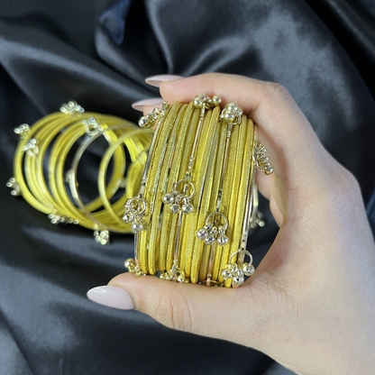 Hand holding gold kashmiri bangles against a dark fabric background